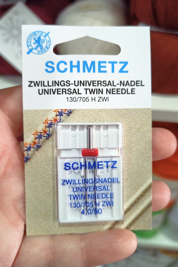 Aguja máquina universal gemela Schmetz. Esta aguja permite hacer 2 pespuntes en paralelos, incluso coser con puntada zig-zag. Mercería en Bormujos. Tienda de hilos y lanas. Casasol. Lanas Mondial